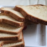 A pear carrot and oats bread loaf sliced on top of a white plate