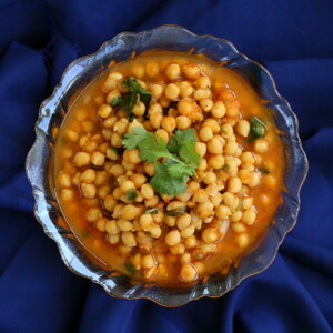 Imli chole served in a bowl on a dark blue background