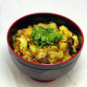 A dark bowl of patta gobi sabzi on a marble countertop