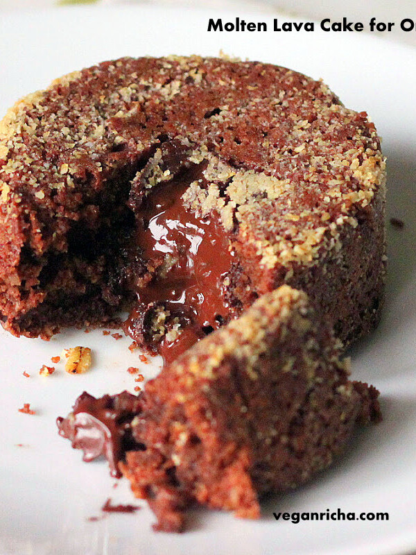 A molten lava cake on a white plate. A piece is broken away to show the melted chocolate centre