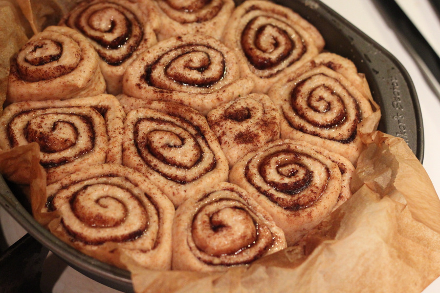 vegan cinnamon rolls risen vegan cinnamon buns in a round cake pan ready to be baked