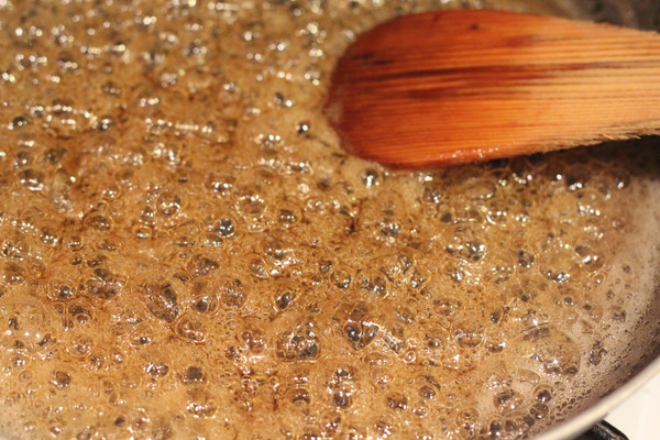 salted caramel brownies vegan coconut caramel sauce being stirred in a sauce pan with a wooden spoon