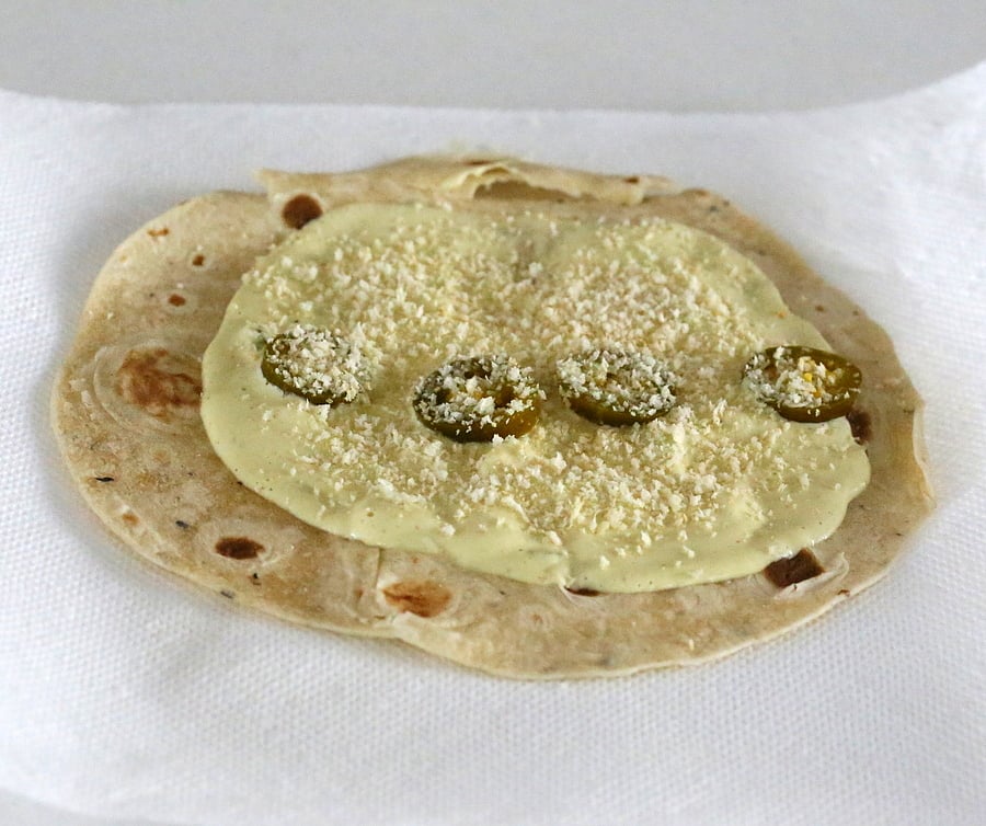 tempeh scramble cashew jalapeno popper dip being spread on a wheat tortilla to make vegan breakfast wrap