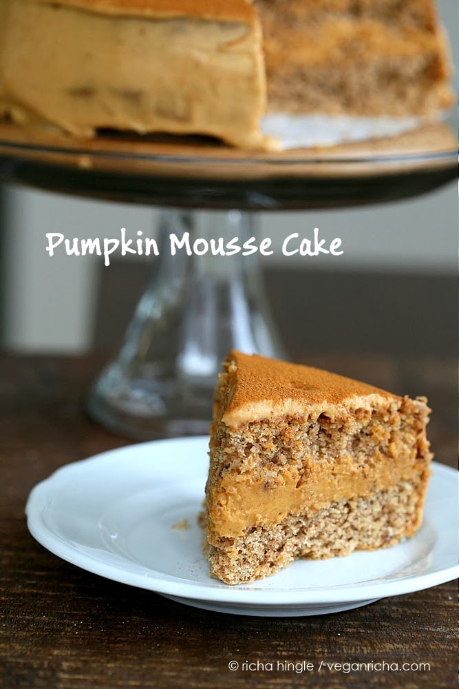 mousse cake a slice of vegan pumpkin cake filled with dairy-free pumpkin mousse on a cake plate with a cake stand in the background