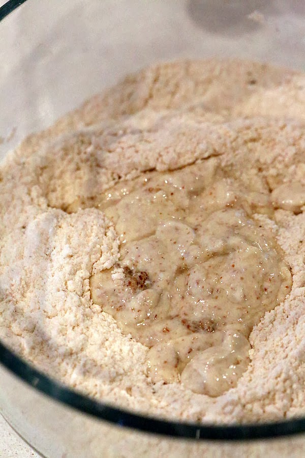 gluten free biscuits recipe wet ingredients being added to dry ingredients in a glass bowl to make gluten free biscuits recipe