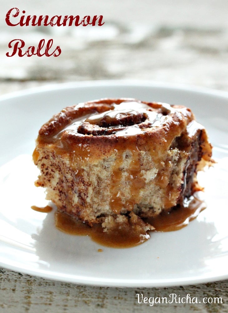 side view of a homemade maple-glazed vegan cinnamon roll on a white plate