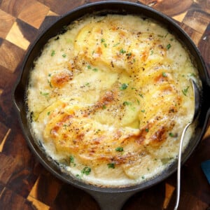 Vegan Scalloped Potatoes in a cast iron skillet on wood board