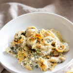 a serving of vegan spinach and artichoke pasta bake on a white plate