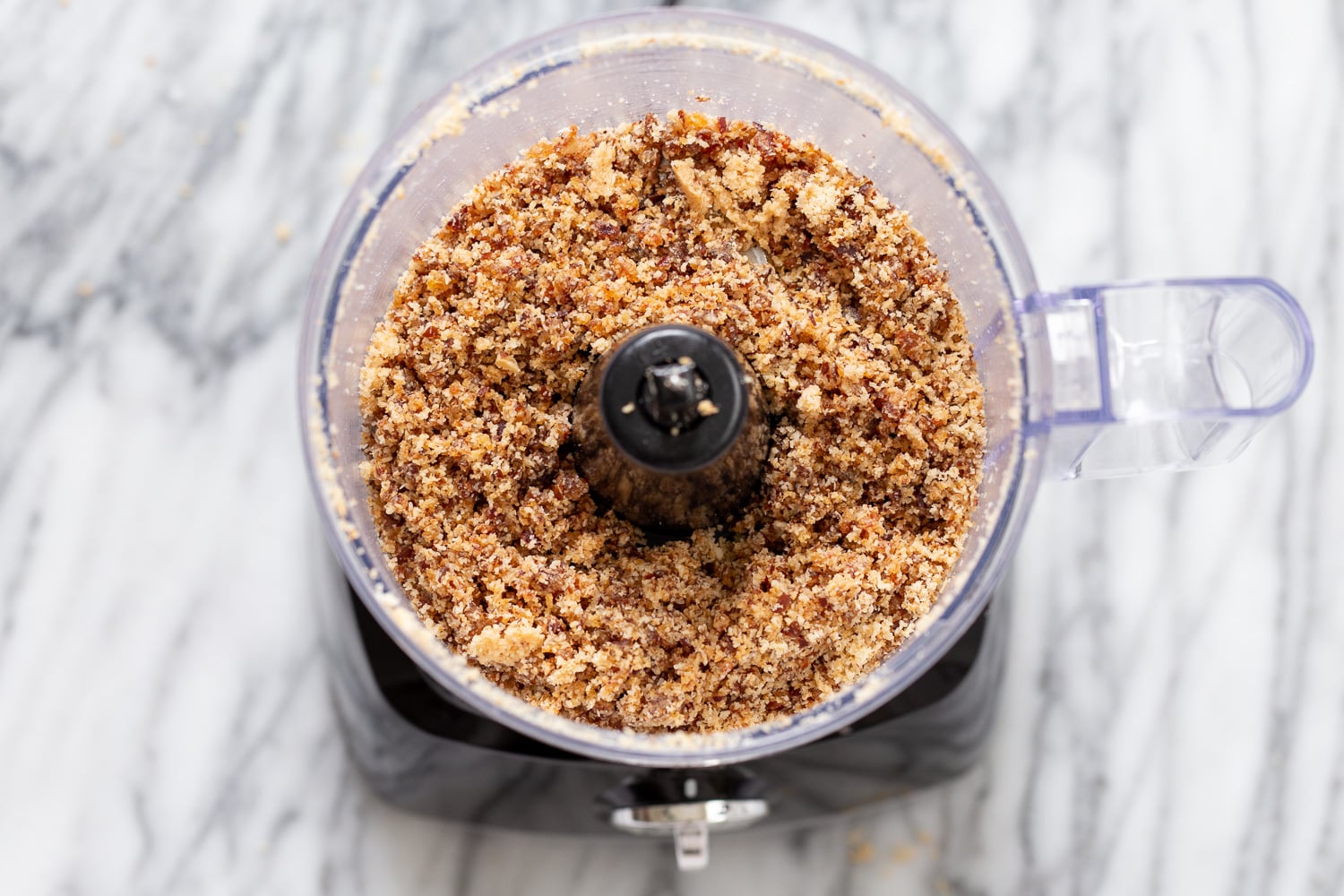 coconut balls shredded coconut and dates in the container of a food processor