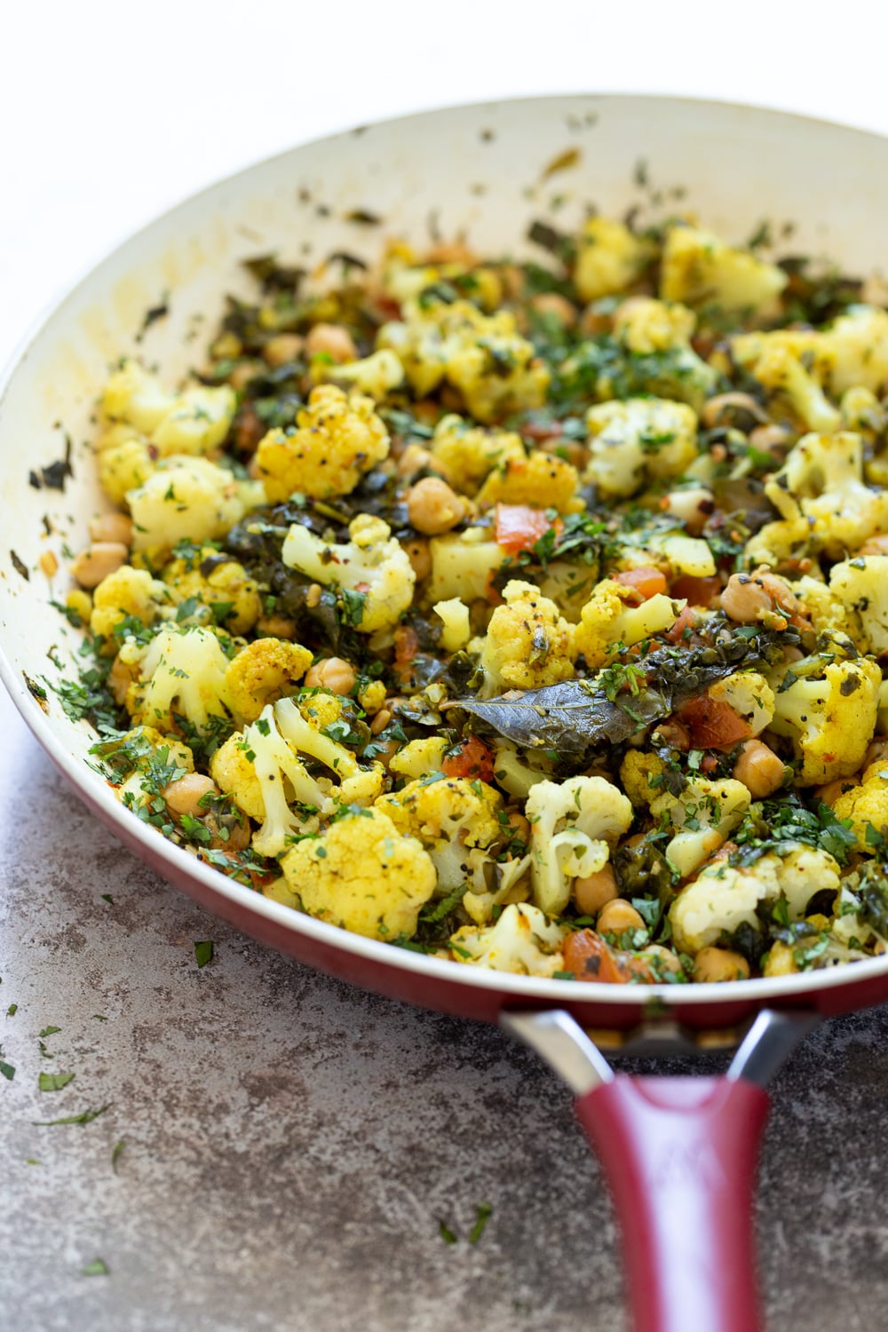 side view of a pan with cauliflower, chickpeas and spinach sauteed with Indian spices 