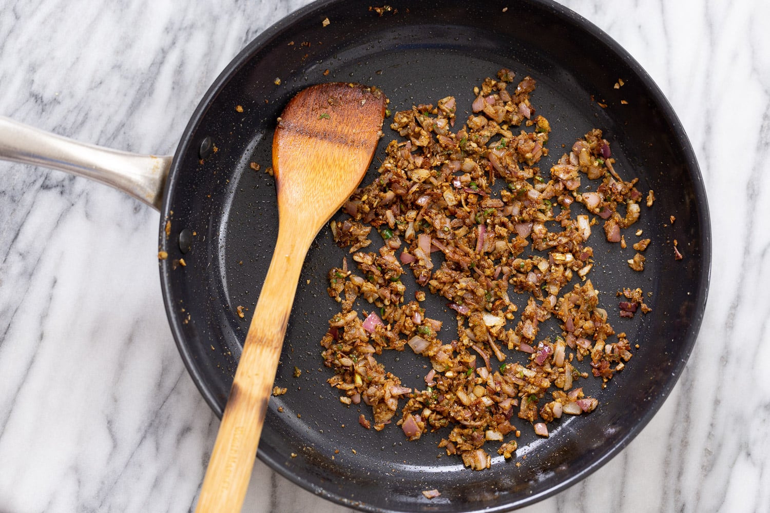 onions, ginger and chili being stir-fried with spices and oil to make tofu in black pepper sauce