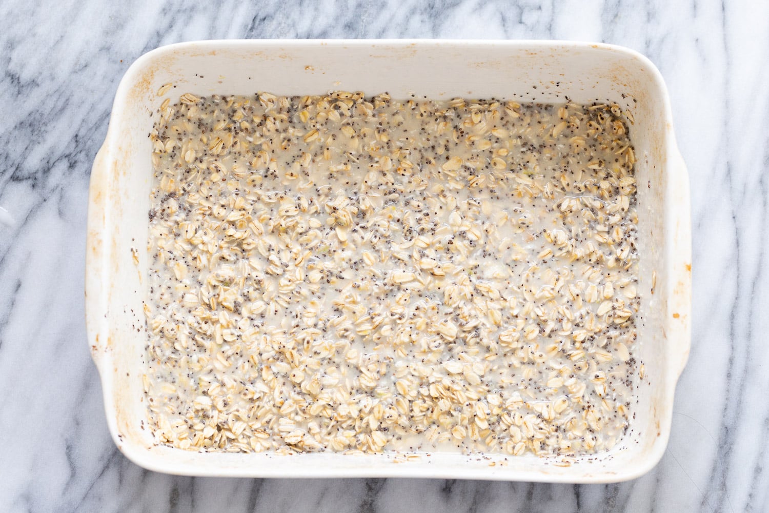 vegan baked oatmeal rolled oats and chia seeds being mixed with plant based milk to make baked oatmeal