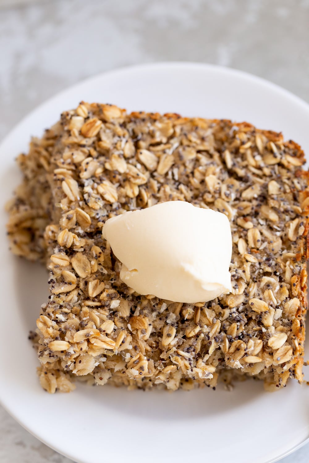 vegan baked oatmeal overhead shot of a square of healthy vegan baked poppyseed lemon oatmeal topped with coconut whipped cream