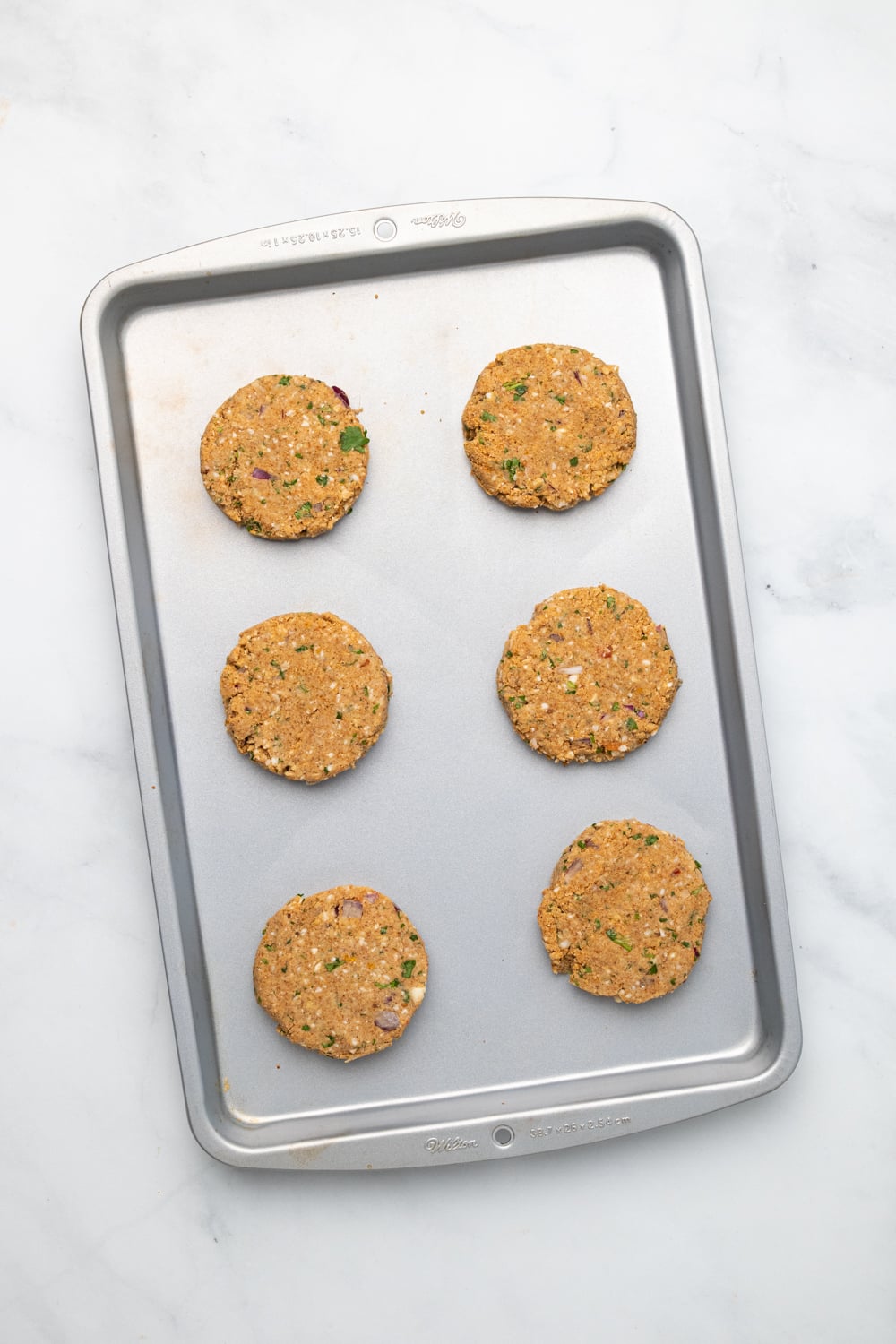 chickpea burger overhead shot of vegan chickpea burger patties lined up on a cookie sheet