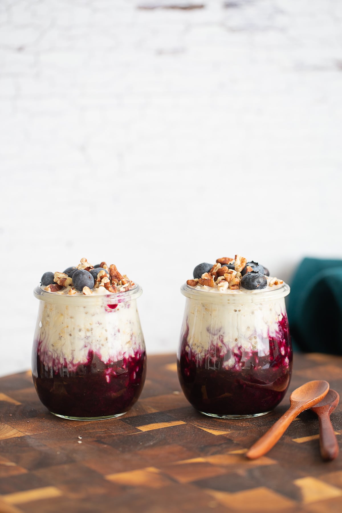 blueberry overnight oats side view of two jars of blueberry overnight oats on a wooden board