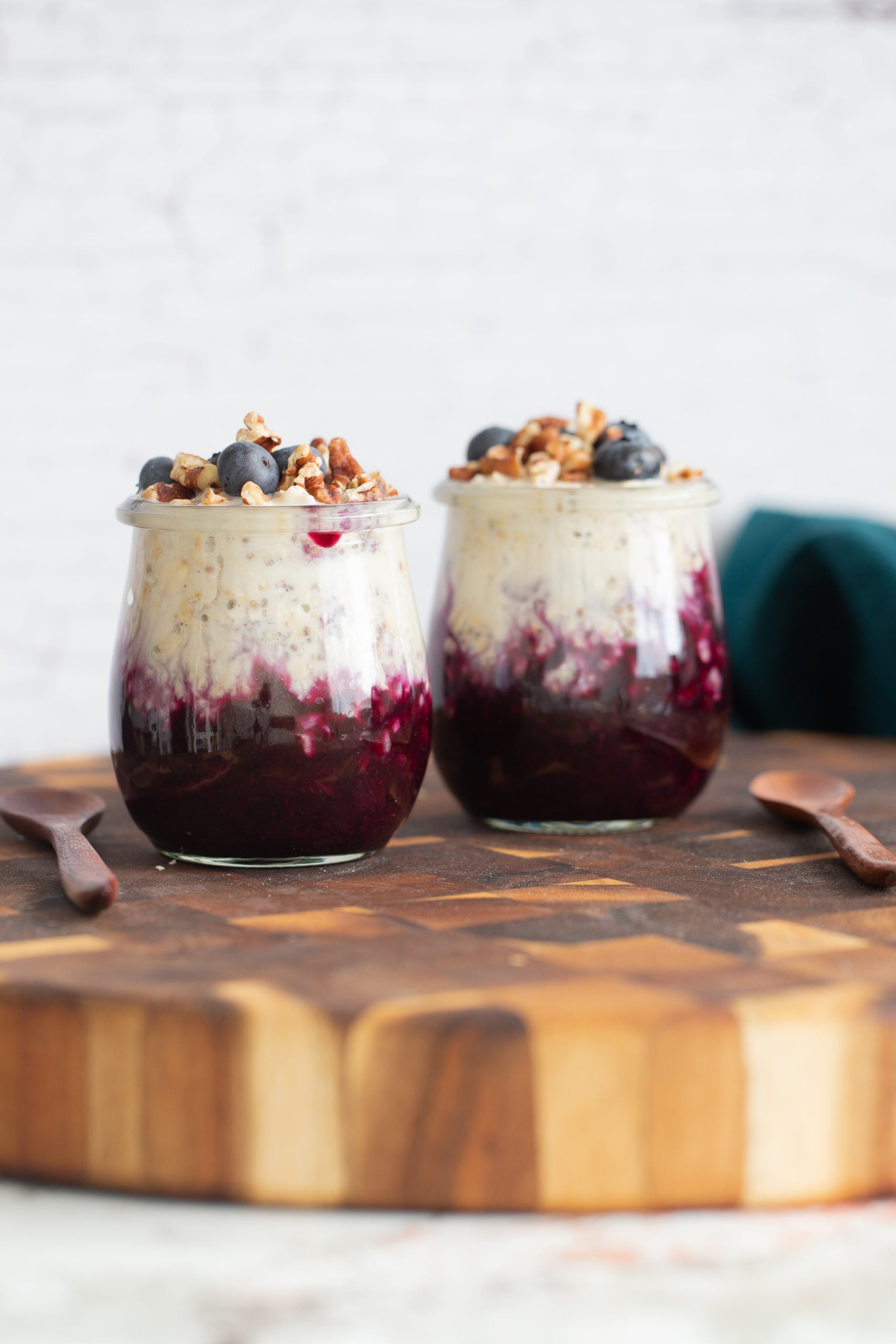 blueberry overnight oats side view of two jars of make ahead vegan blueberry muffin overnight oats on wooden board