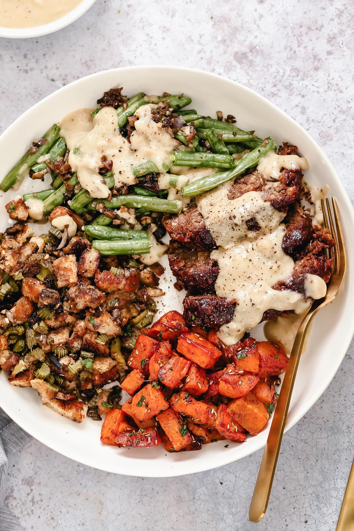overhead shot of vegan sheet pan Thanksgiving dinner with lentil loaf and three sides all served in a plate 