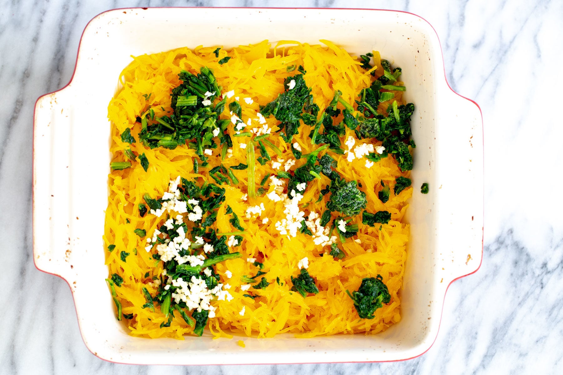 spaghetti squash bake cooked spaghetti squash, spinach and garlic in a white casserole dish
