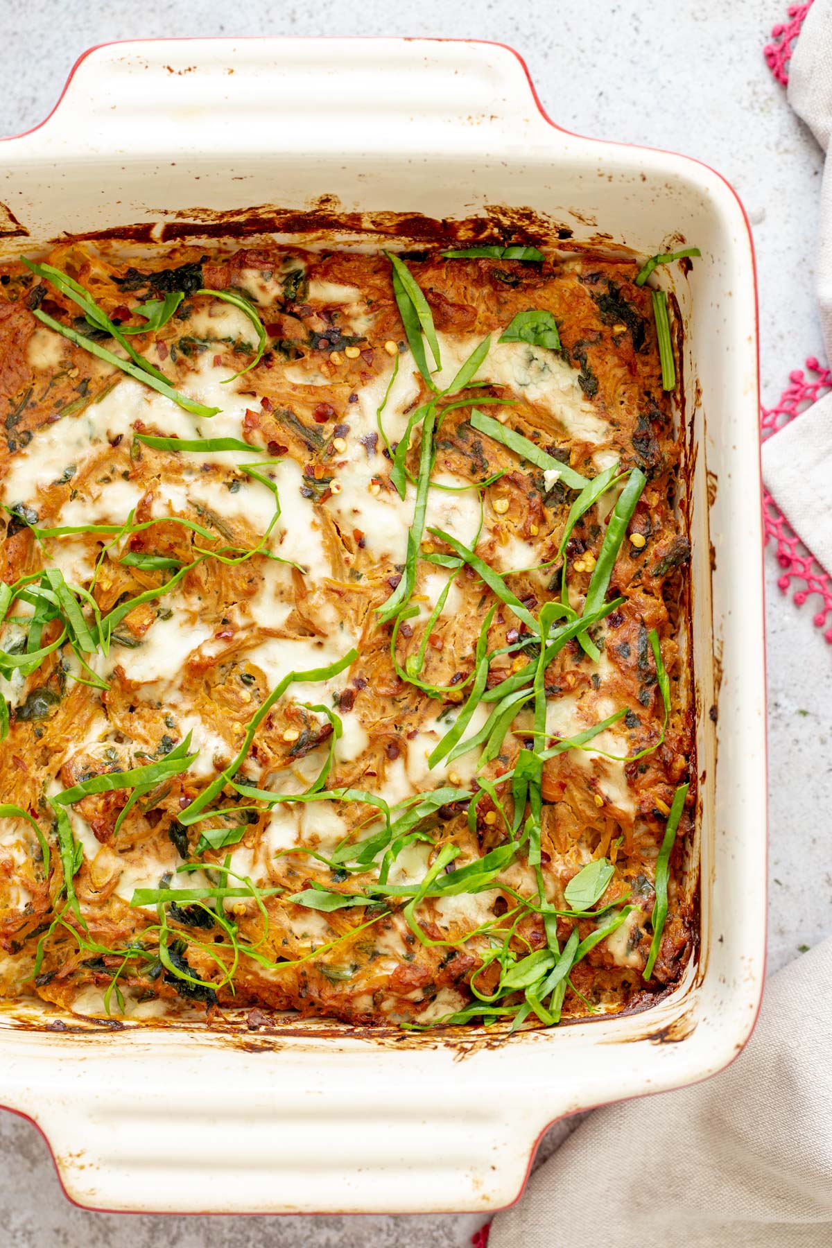 spaghetti squash bake overhead shot of a casserole dish with vegan spaghetti squash bake sprinkled with fresh chopped basil