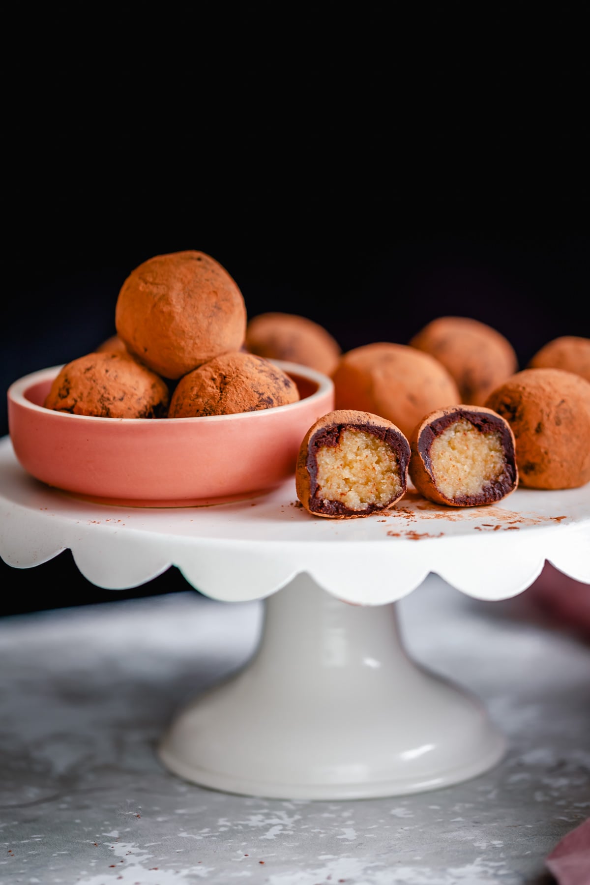 vegan tiramisu truffles on a cake stand with one truffle cut open
