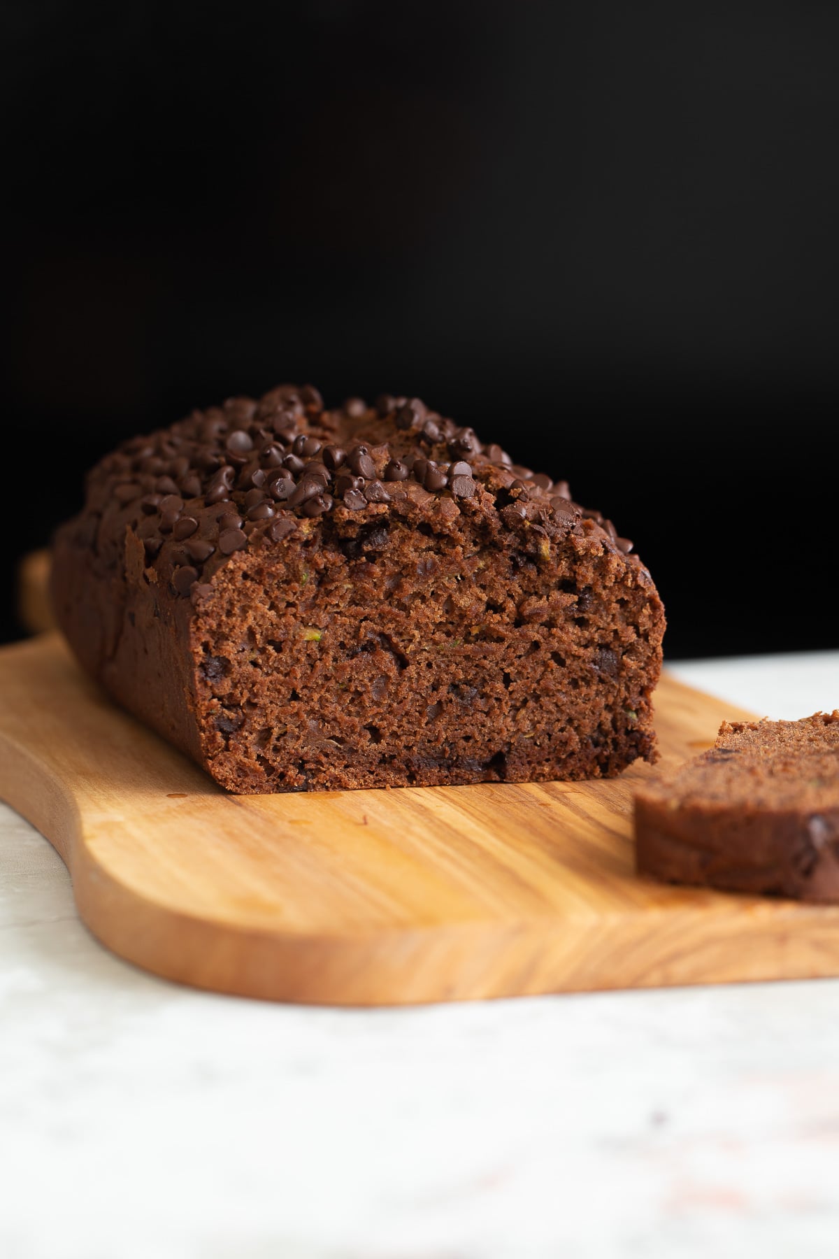 side view of a loaf of moist vegan chocolate zucchini bread with one slice cut
