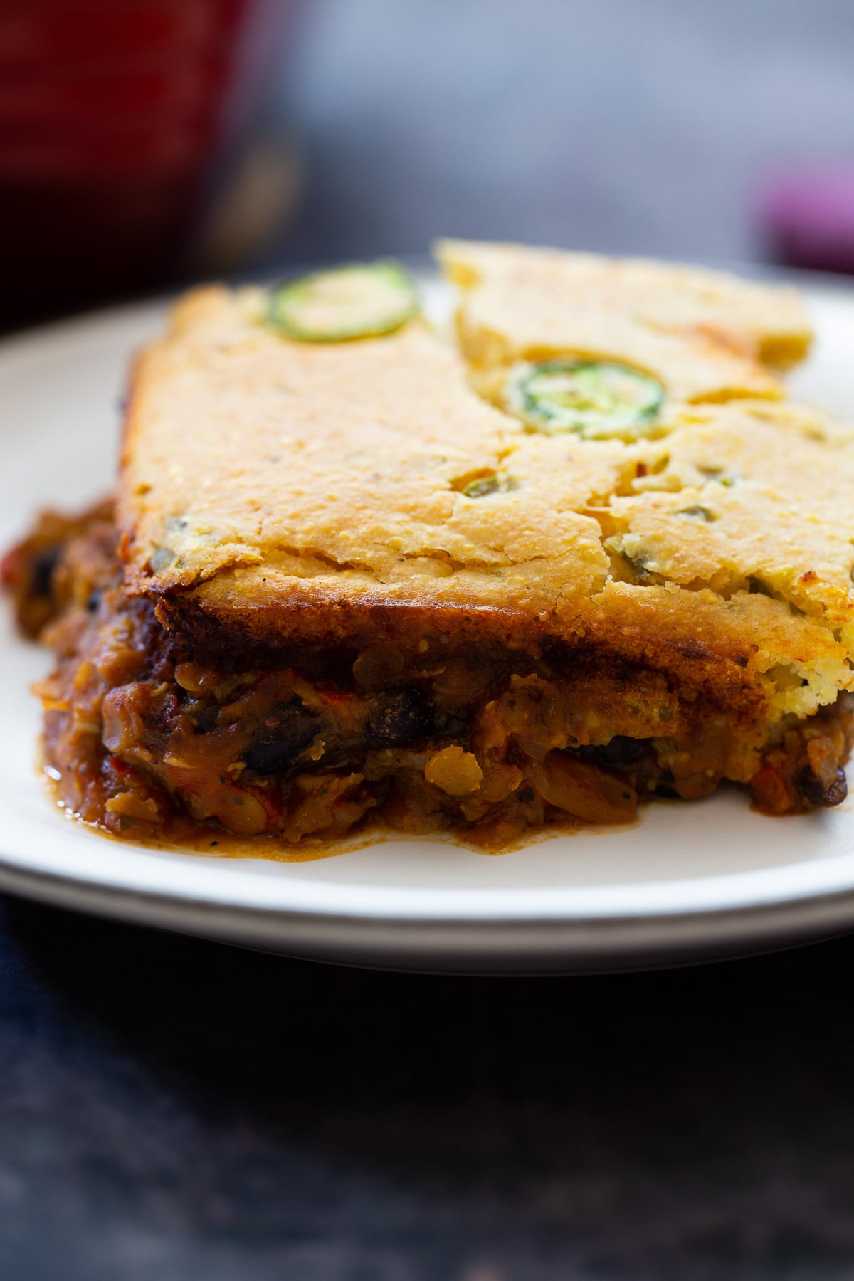 side view of a square of chili cornbread casserole on a white plate