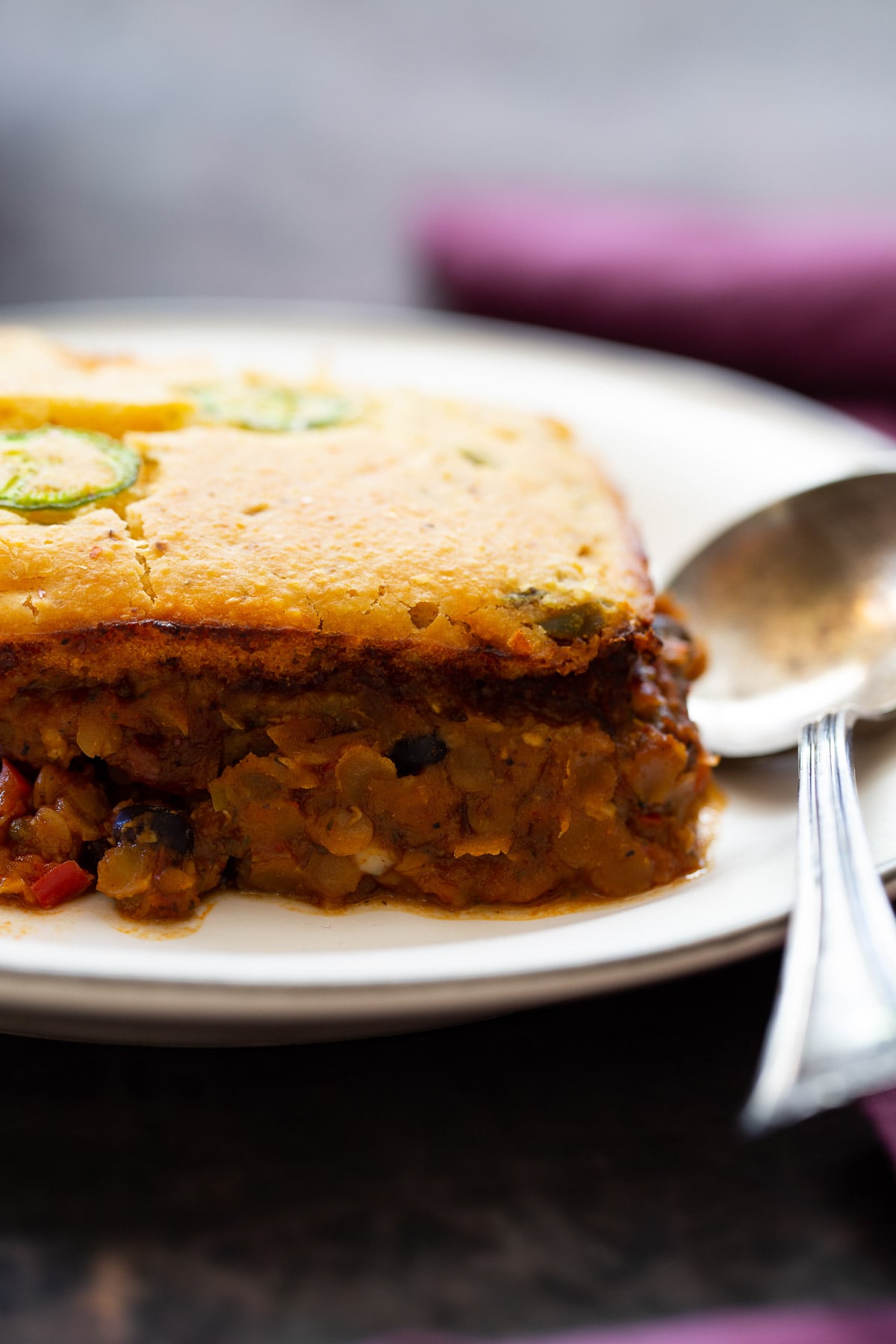  side view of a slice of chile cornbread casserole on a white plate