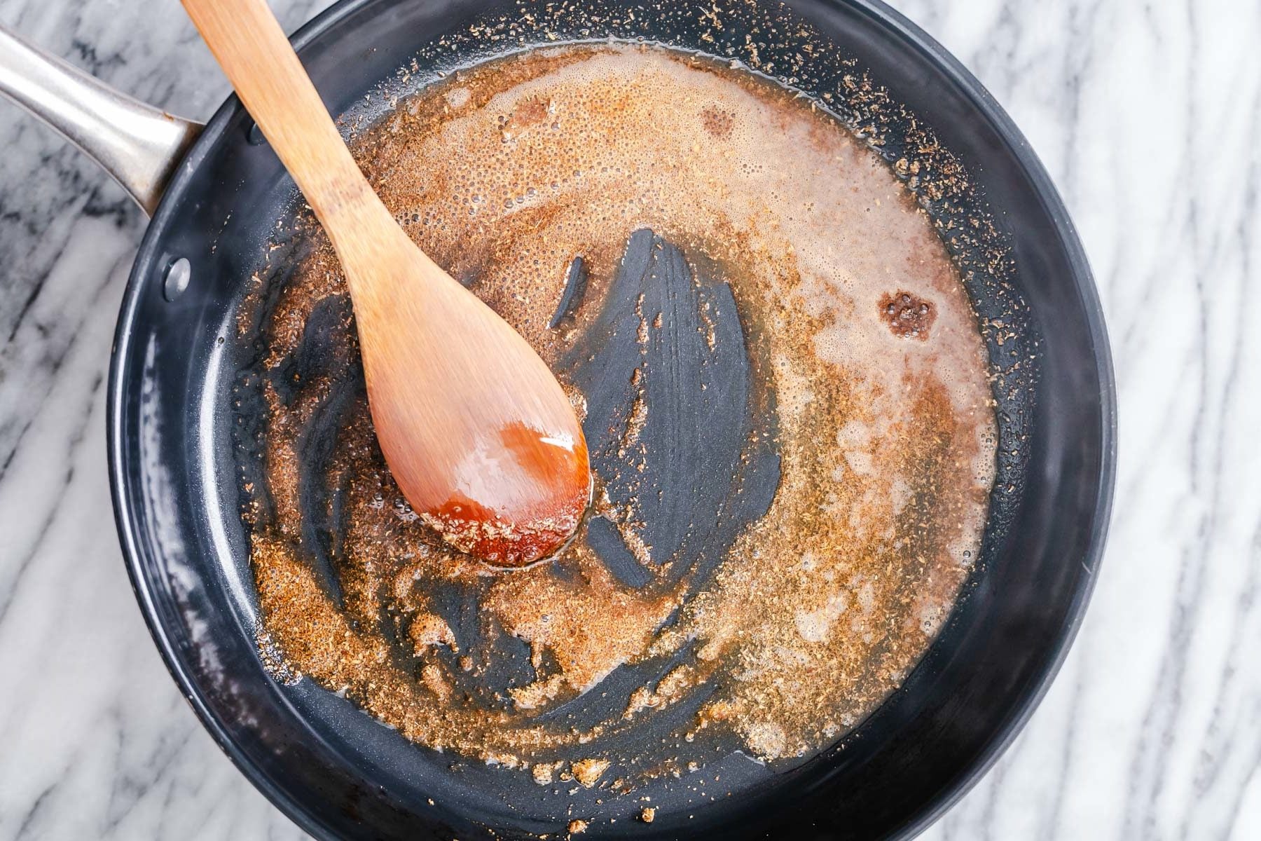 Indian spices being tempered in a black frying pan
