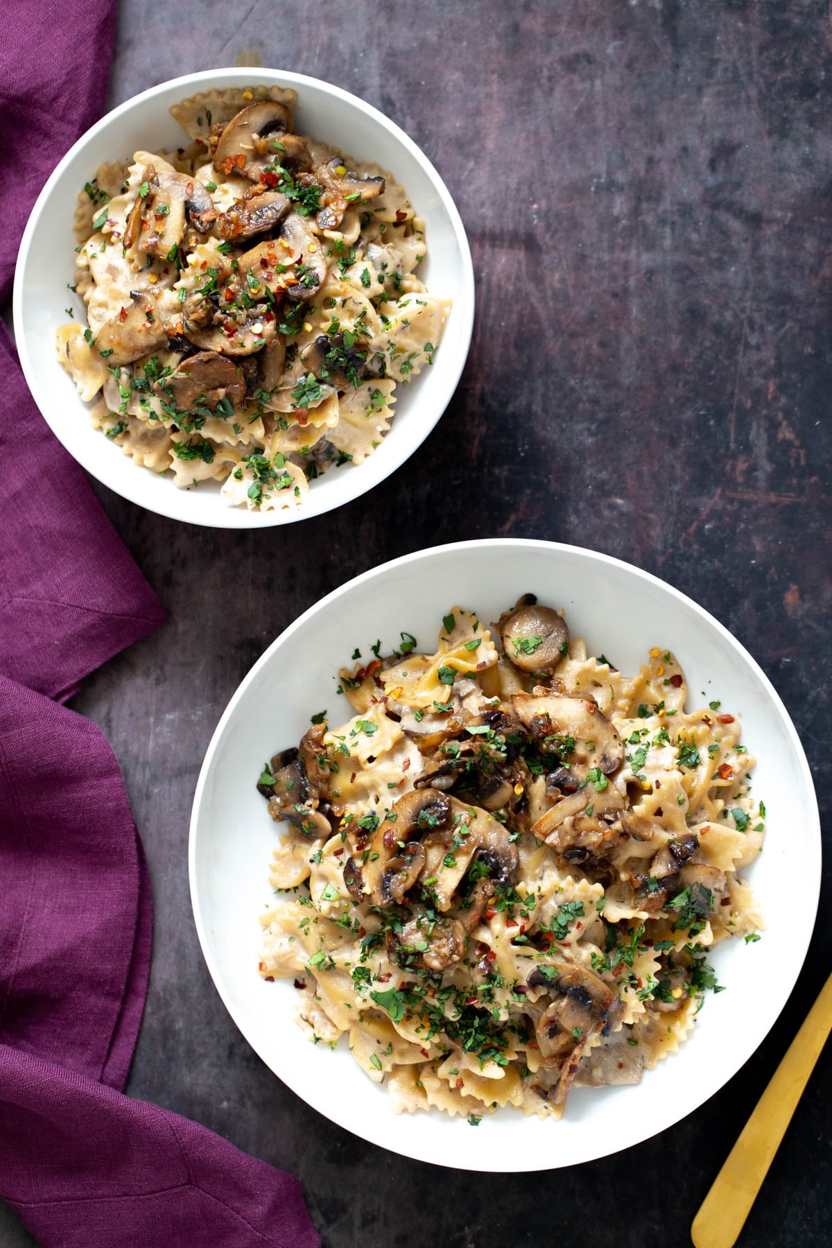 two plates with farfalle pasta topped with vegan mushroom stroganoff