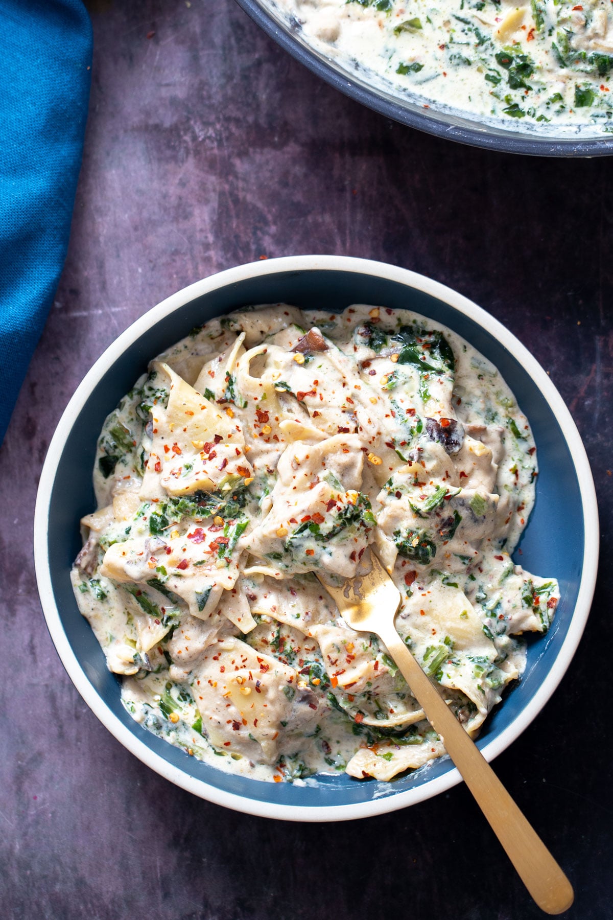 a serving of vegan alfredo spinach skillet lasagna on a blue plate 