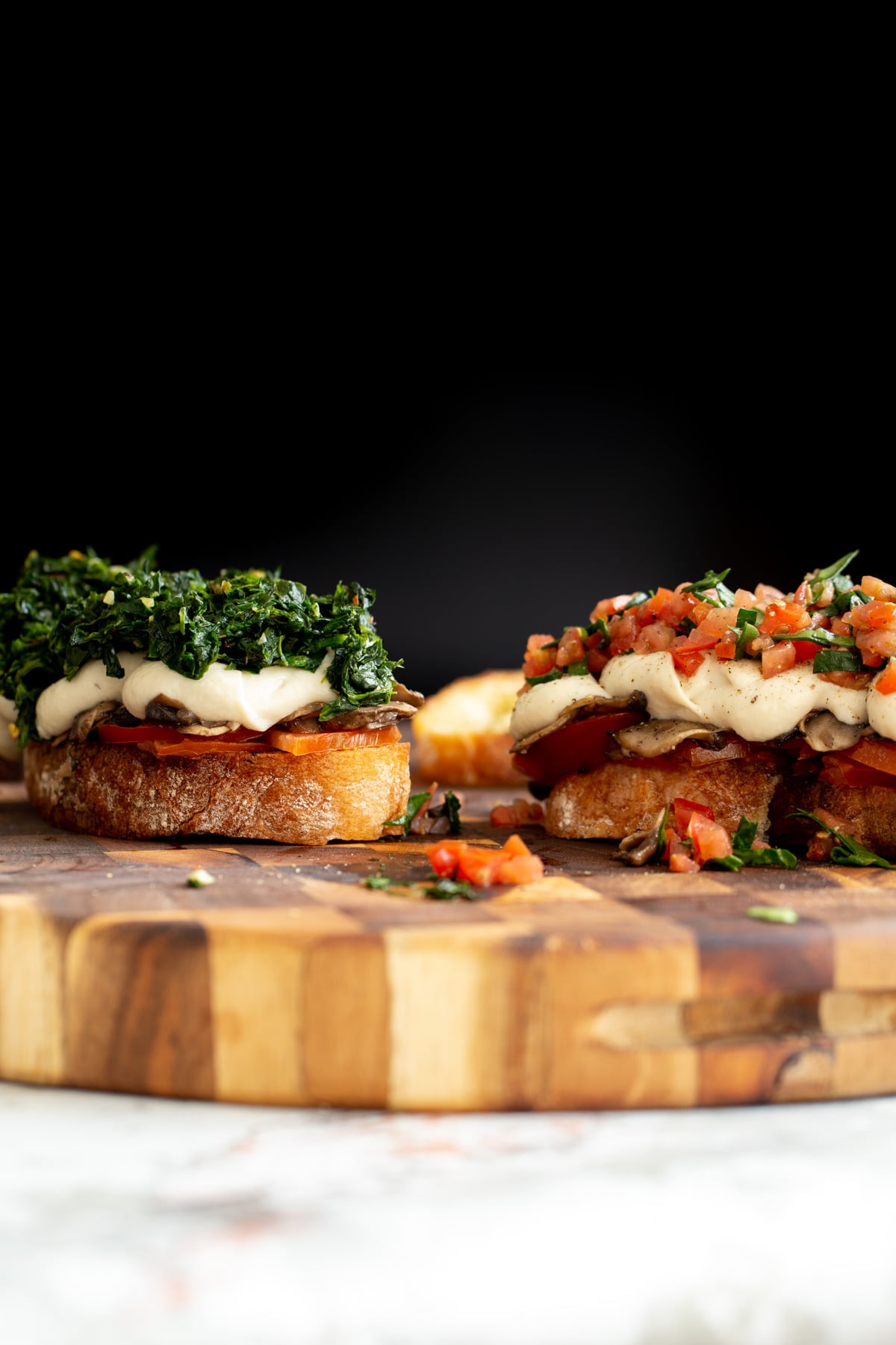vegan cheese melts side view of vegan cheese melts topped with spinach and chopped tomatoes