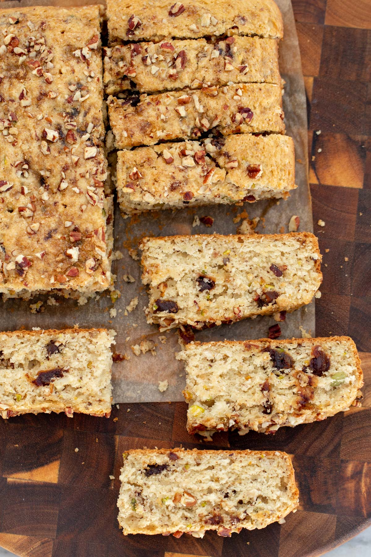 vegan date nut cake being cut into slices on a wooden board