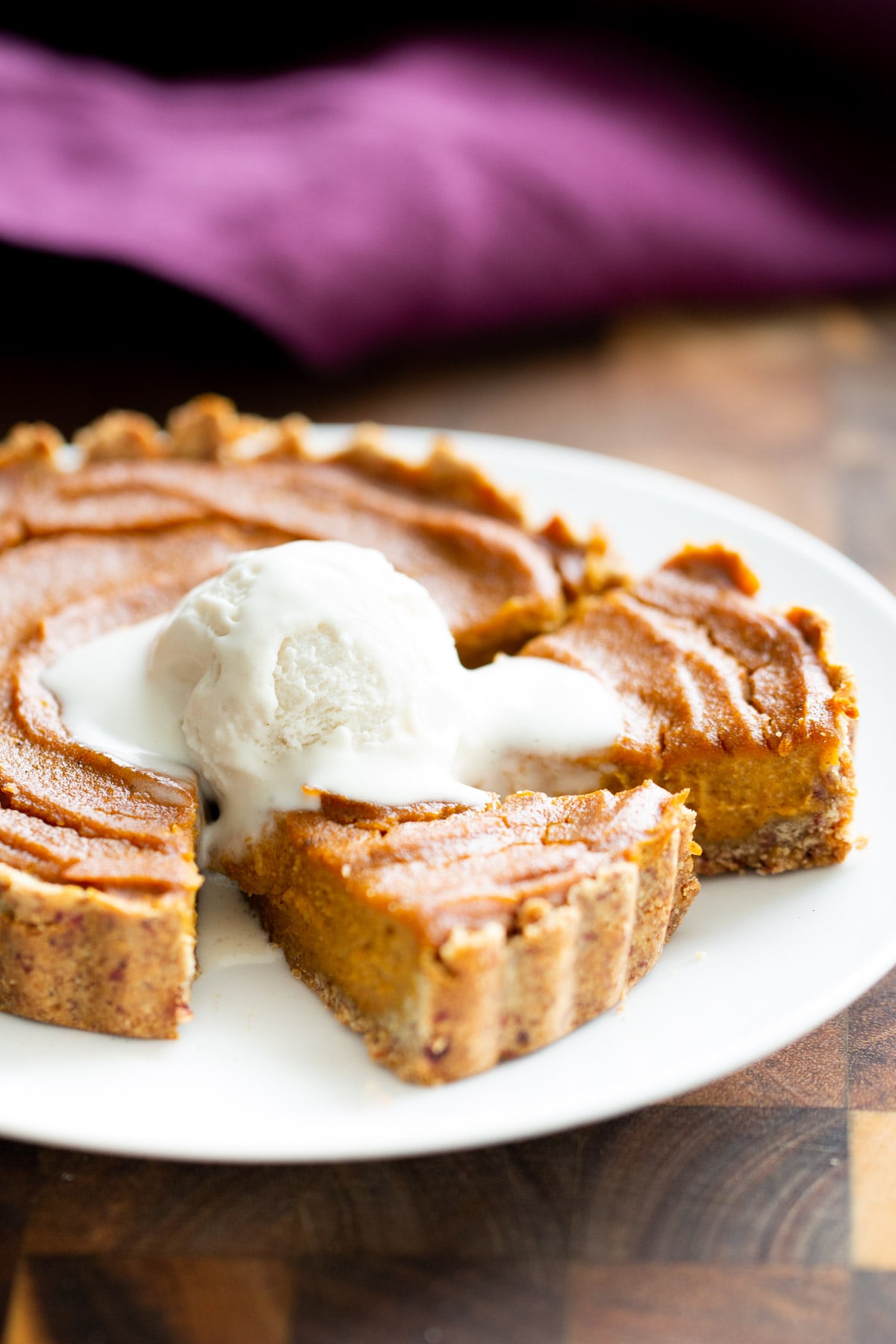 a small gluten free vegan pumpkin pie served with some vegan ice cream 