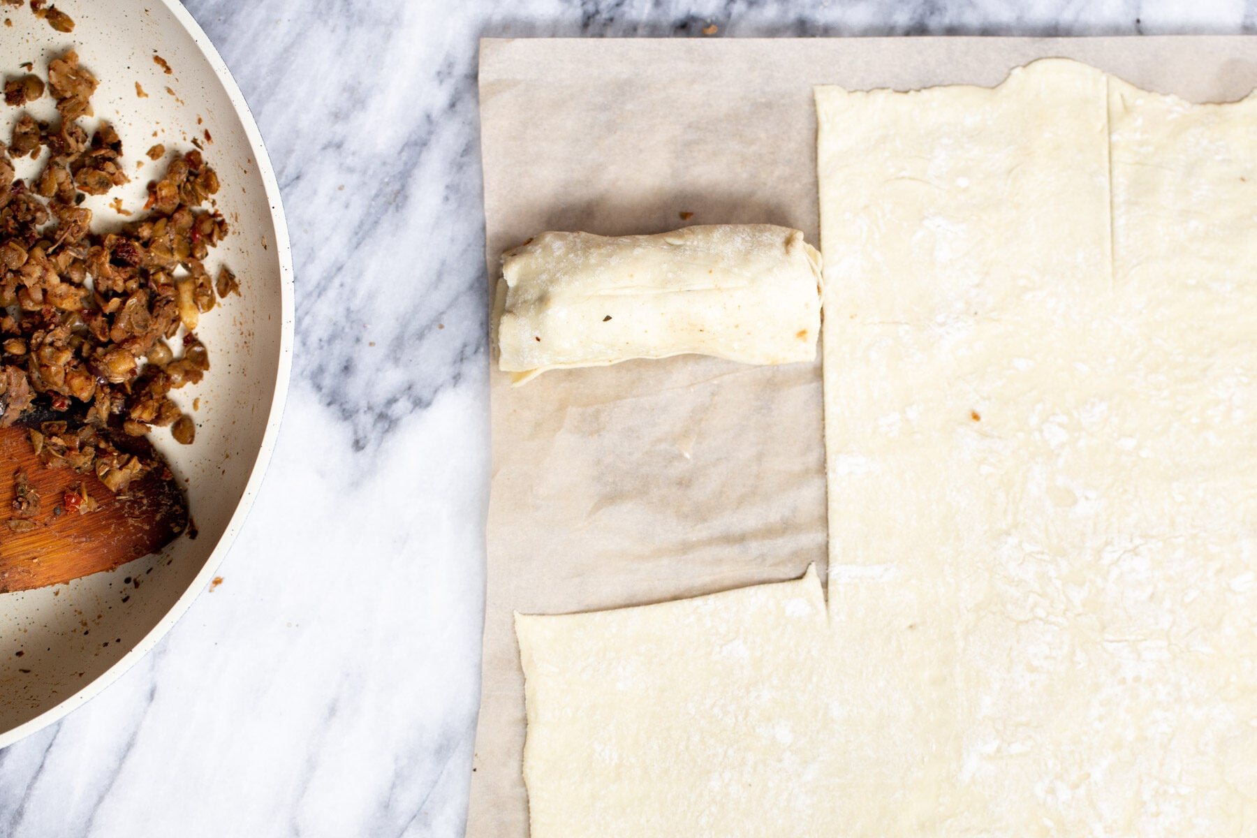 vegan sausage rolls thawed puff pastry being rolled out on a marble countertop