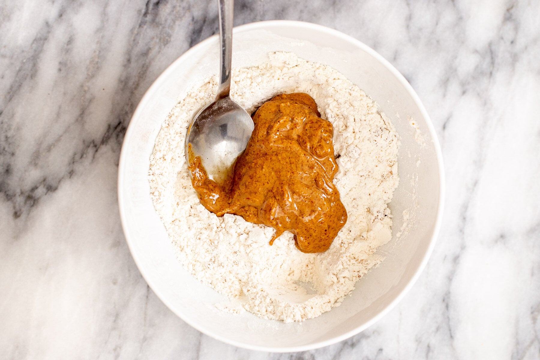 almond butter being mixed into dry crumble crust ingredients