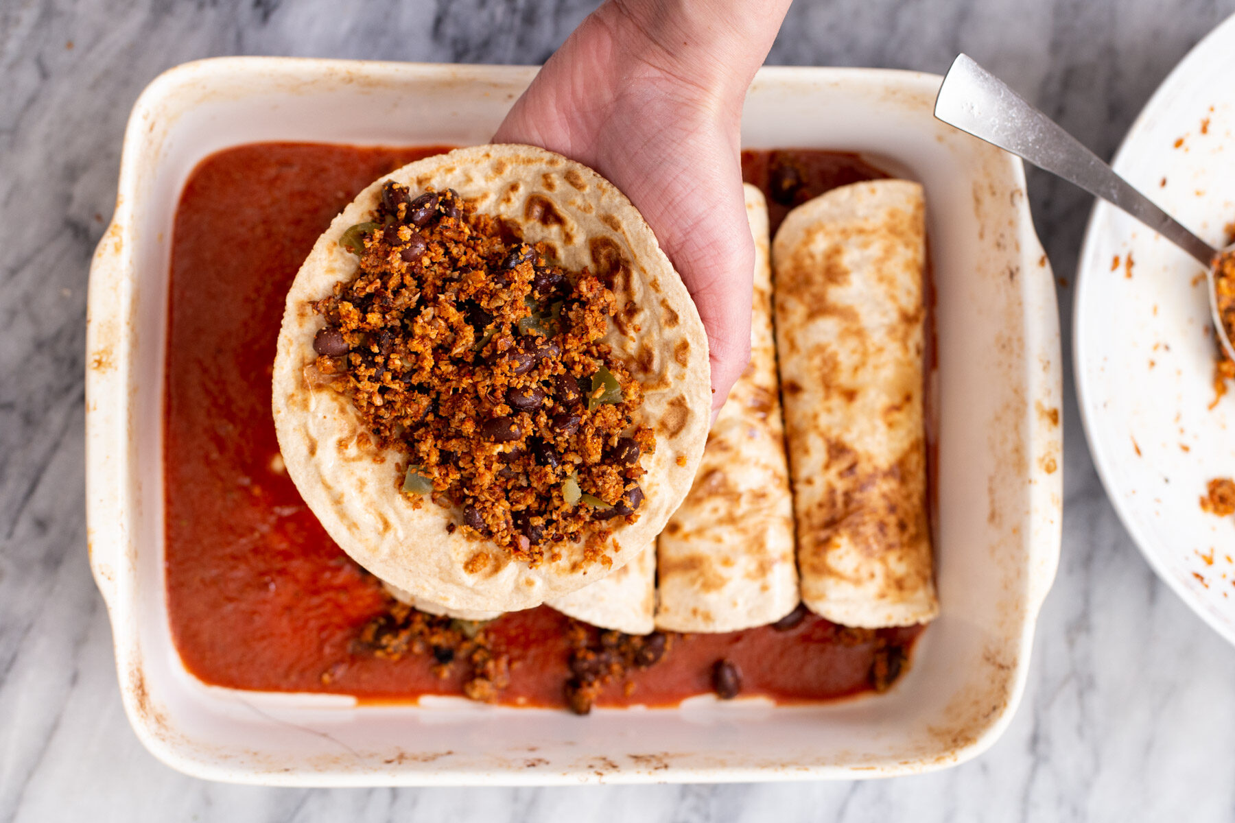 a hand holding a wheat tortilla filled with vegan cauliflower taco meat