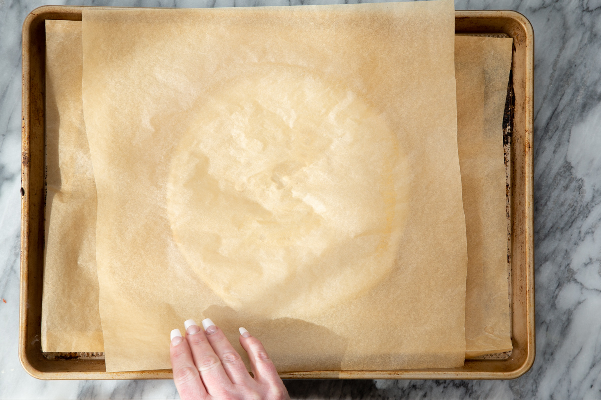 parchment paper being placed on an round of almond flour pizza crust