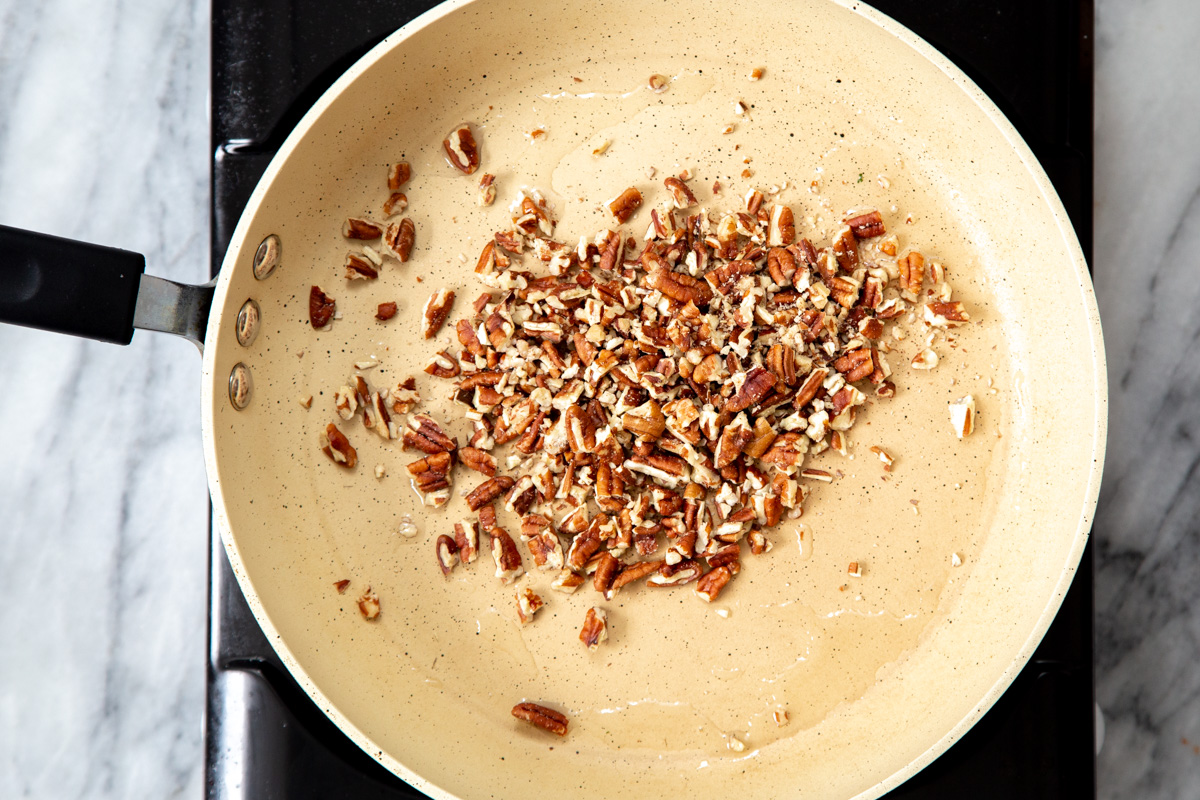 chopped pecans being toasted in a pan.