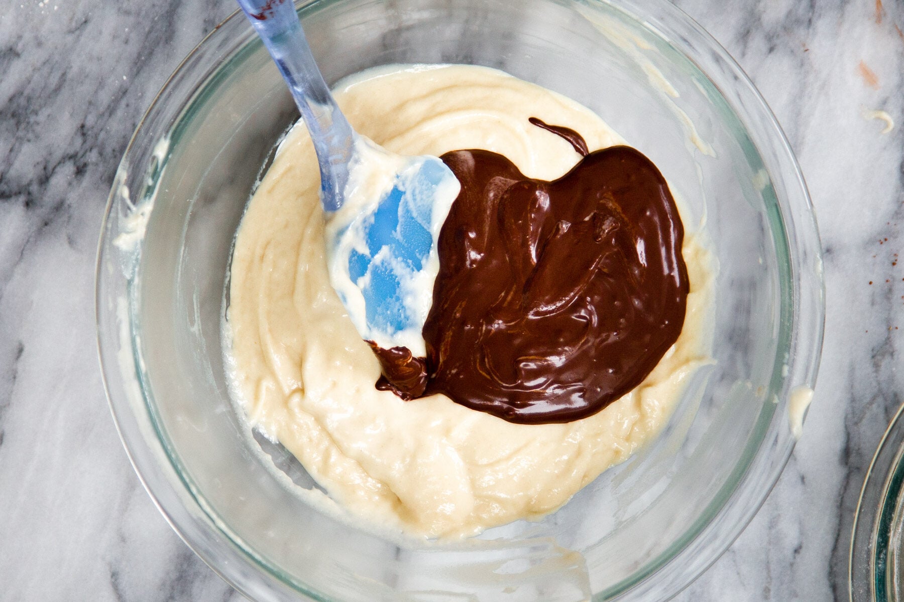 chocolate cake batter being added to vanilla cake batter 