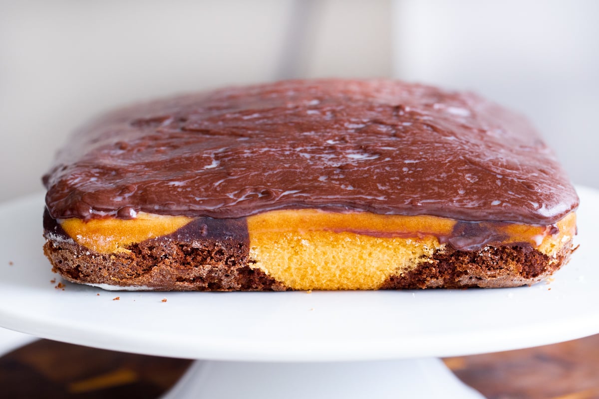 chocolate ganache being spread on marble cake 