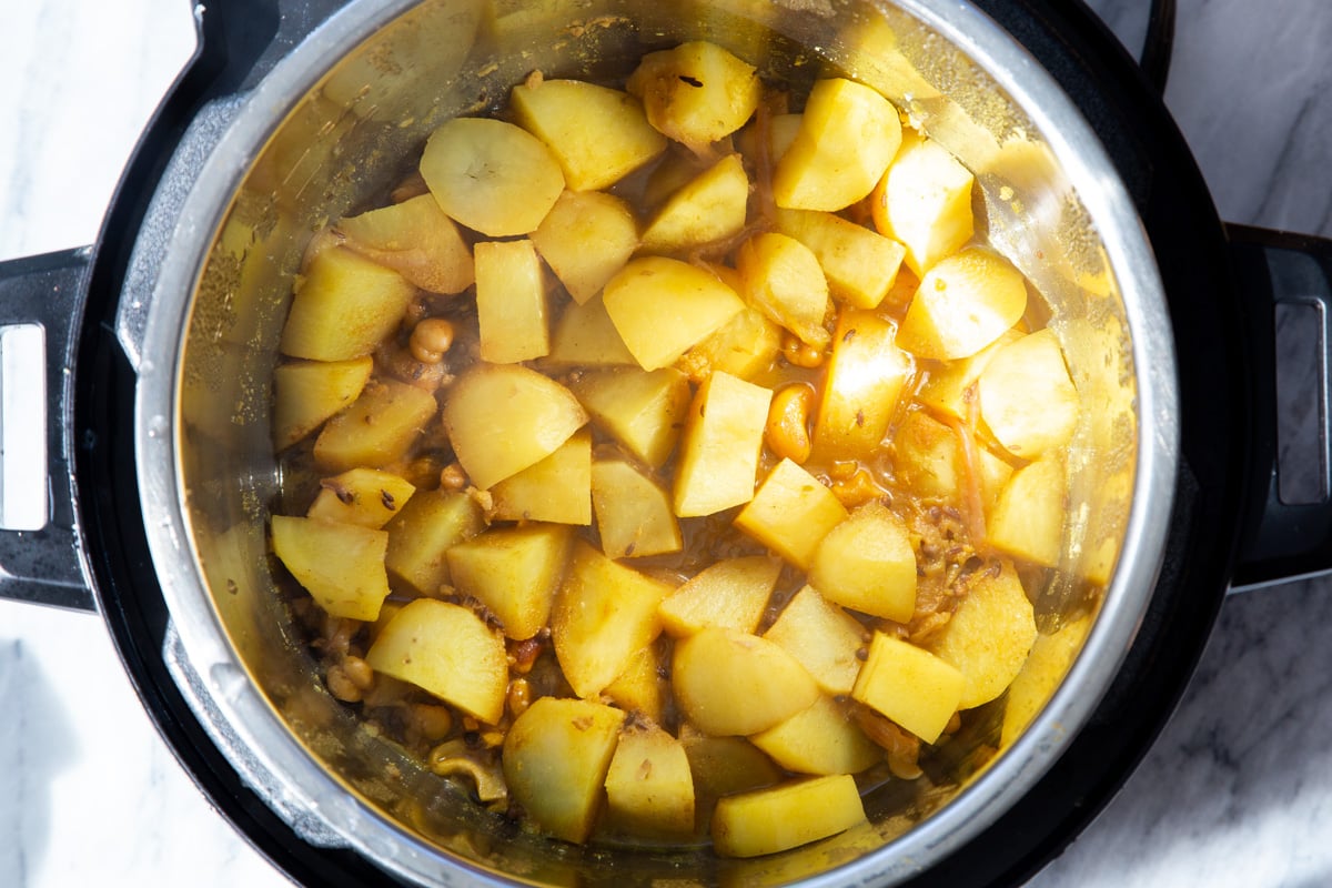 potatoes simmering with spices and cashews in an Instant Pot 