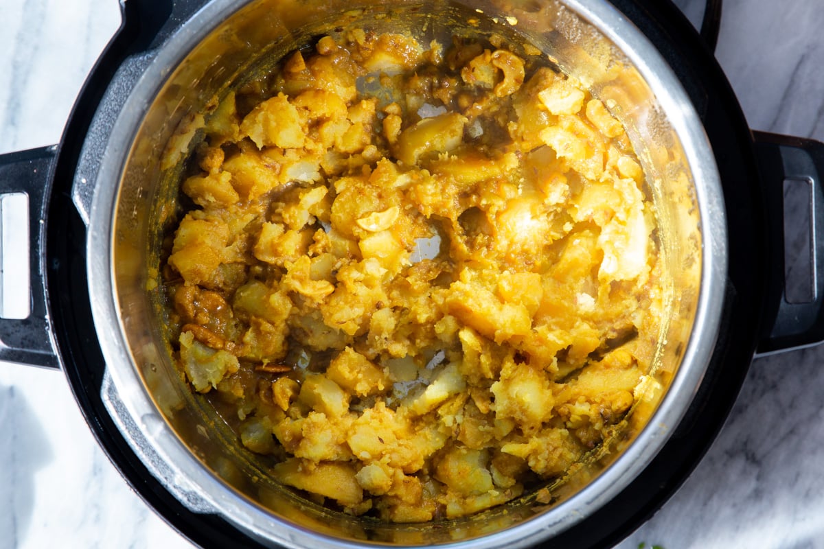 potatoes being mashed in an Instant Pot to make samosa filling 