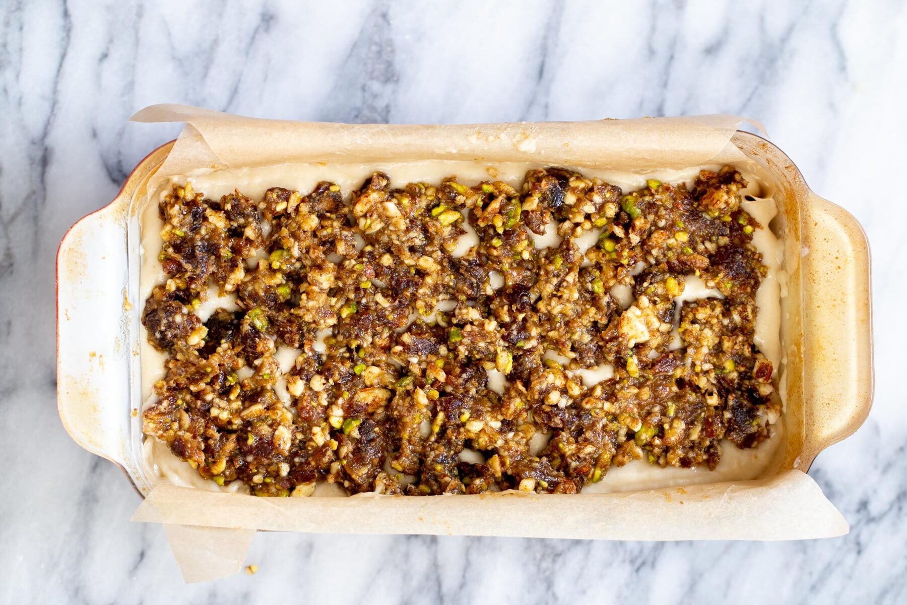 cake batter being topped with baklava topping 