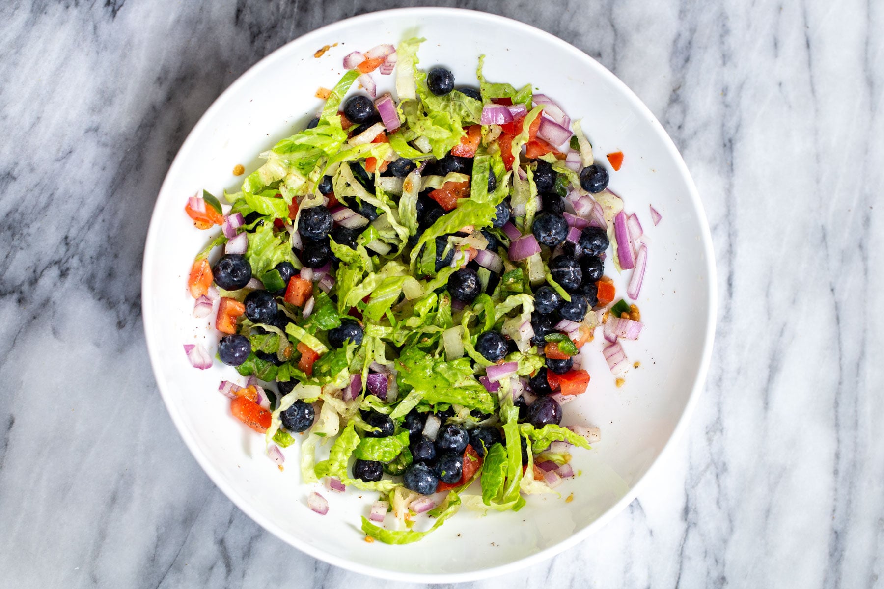 blueberry tomato salad in a white bowl