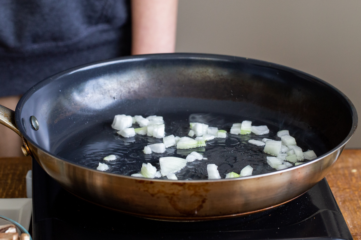 minced onions being sauteed in a black skillet