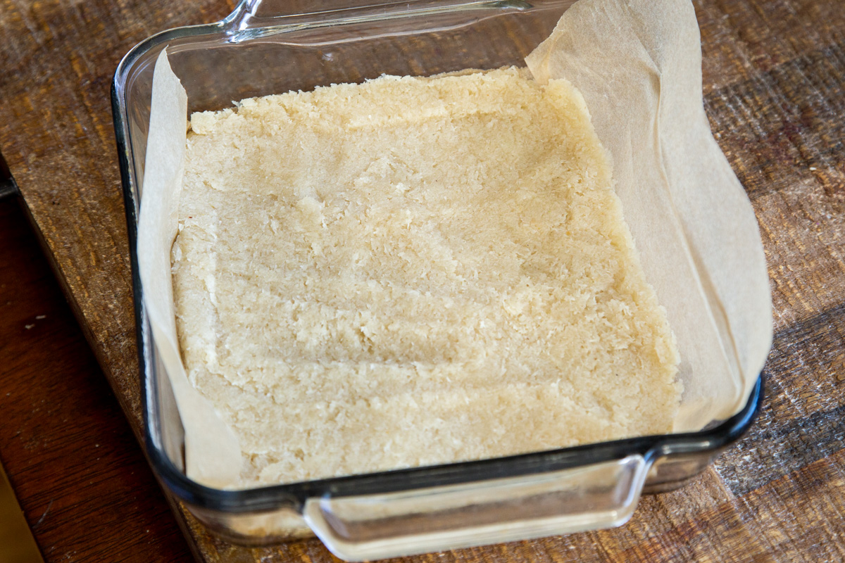 coconut burfi batter being pressed into a rectangular pan