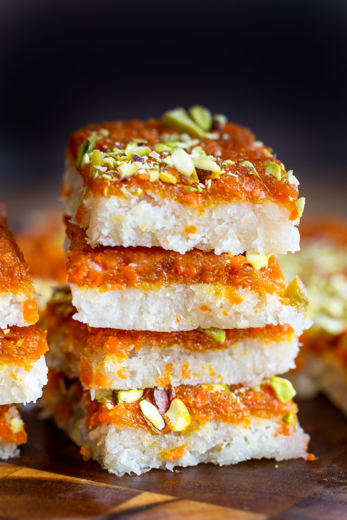 a stack of carrot halwa coconut burfi bars topped with pistachios