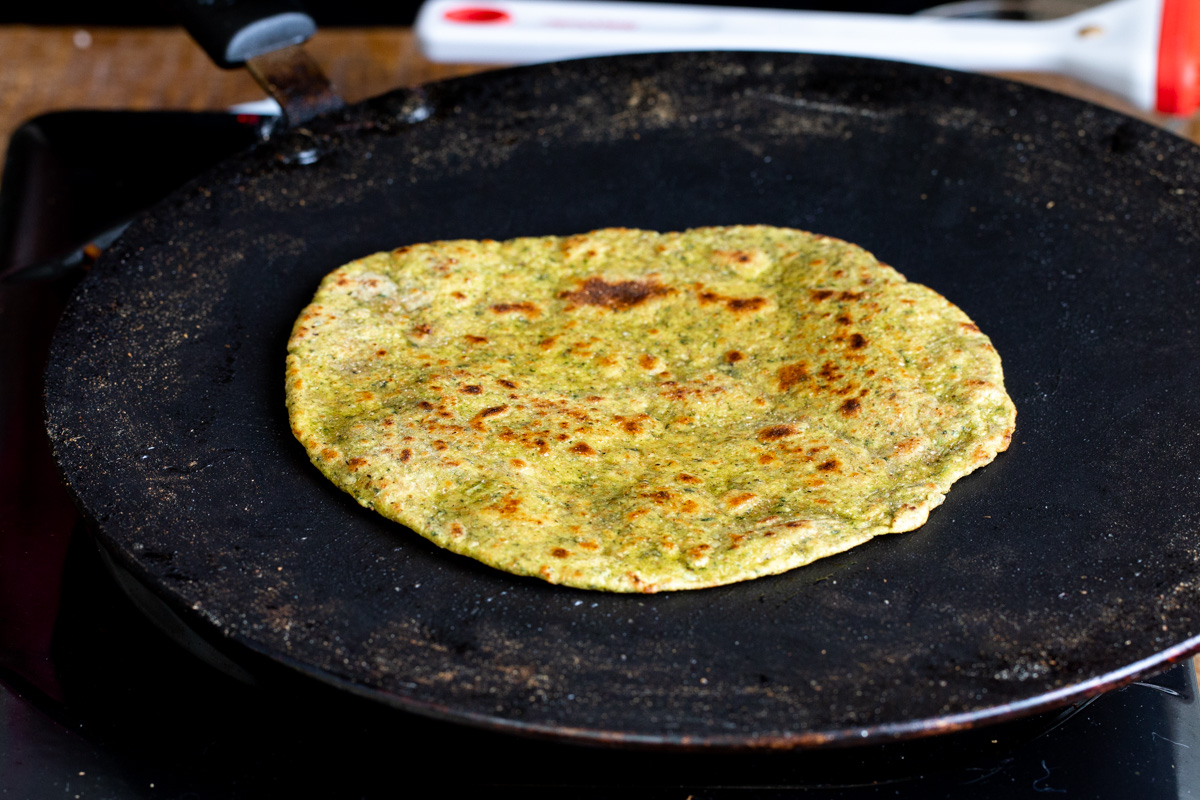 freshly toasted masala paratha in a black flat skillet
