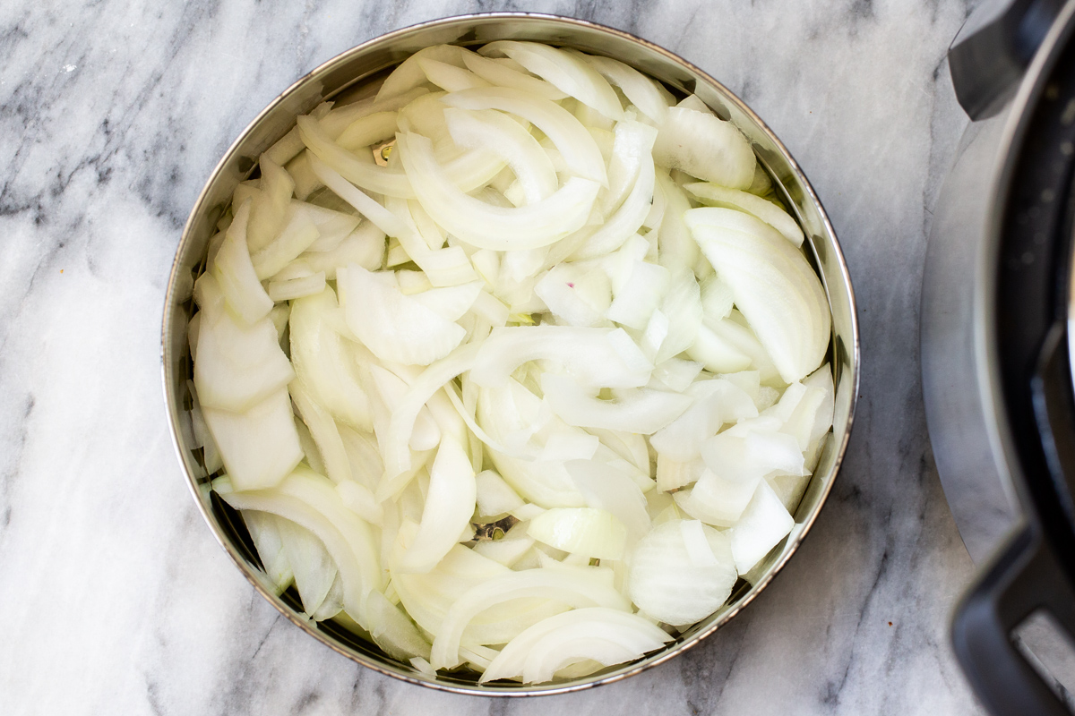 sliced yellow onion in the inner pot of an Instant Pot