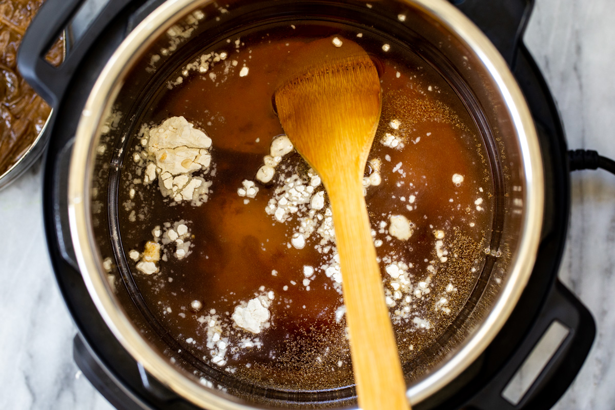 broth and flour being added to an Instant Pot to make vegan French Onion Soup